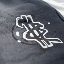 Load image into Gallery viewer, Close-up of a logo on a dark fabric surface
